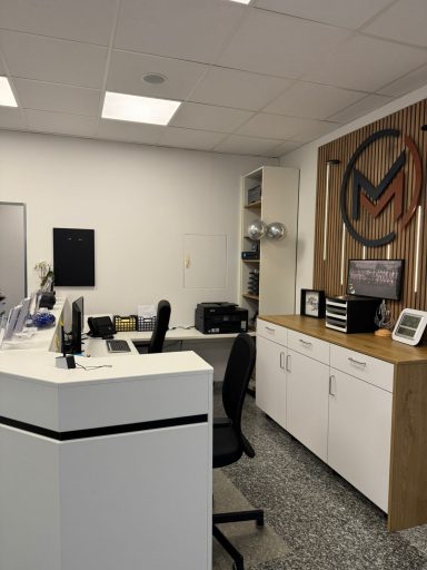 Moderne Büroumgebung mit Schreibtisch, Computer und Holzregal.